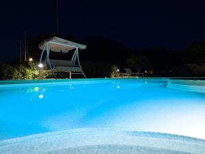 Káto SangríonNaxos Cottage的夜间大型蓝色游泳池,带雨伞