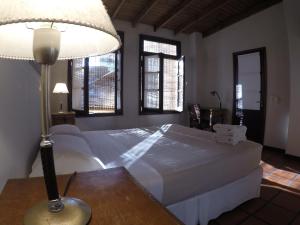 布宜诺斯艾利斯波萨达高登酒店的一间卧室配有一张床和一张桌子上的台灯