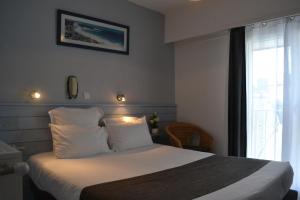 圣皮耶尔基贝龙Hotel De Bretagne的卧室配有带白色枕头的床和窗户。