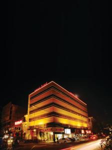 拉合尔Smart Hotel的街上的一座大建筑,晚上有黄色的灯光