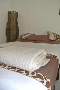 拉巴萨友好北部饭店的一间卧室配有两张带棕色和白色床单的床