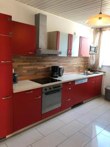 OststeinbekApartment BLN的厨房配有红色橱柜和炉灶烤箱