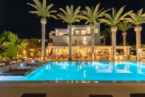 玛利亚Drossia Palms Hotel and Nisos Beach Suites的夜间有游泳池和棕榈树的酒店