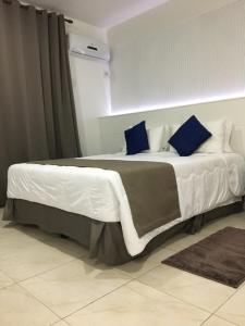 波苏阿莱格里Fenix Hotel Pouso Alegre的一间卧室配有一张带蓝色枕头的大床