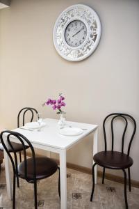 伊万诺-弗兰科夫斯克Apart Reserve Sloboda Klassik的一张带两把椅子的白色桌子和墙上的时钟