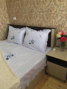 阿哈尔齐赫HOTEL JULIA Akhaltsikhe的一张带白色枕头的床和花瓶