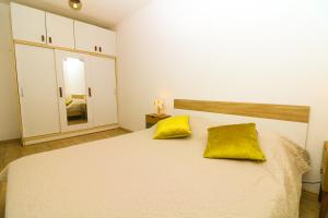 巴斯卡Apartments Andrea的卧室配有白色床和2个黄色枕头