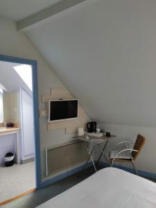 穆瓦朗－昂蒙塔涅勒拉库松酒店的卧室配有一张床,墙上配有电视。