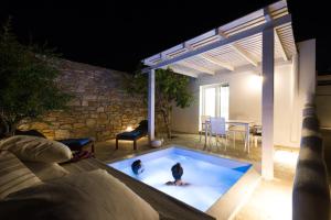 瓦里Syros village suites的两个孩子晚上在后院的游泳池玩耍