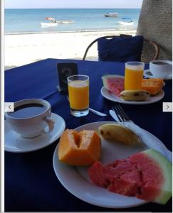 南威Ebony & Ivory Beach Bungalows的一张桌子,上面放着两盘水果和一杯咖啡