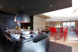 马尔桑奈拉科特第戎南马萨尼钟楼酒店的餐厅在带红色椅子的柜台上供应食物