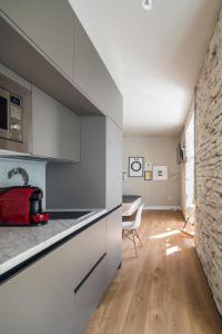 布尔戈斯APARTAMENTOS ELEVEN ROOMS的厨房配有白色橱柜和石墙