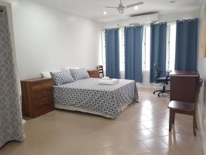 霍尼亚拉Prestige Apartments - Solomon Islands的一间卧室配有一张带蓝色窗帘的床和一张书桌