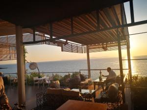 斯卡费迪亚爱奥尼亚马雷代套房度假酒店的坐在有海洋背景的餐厅里的人