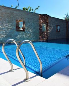 埃里温阿勒珀酒店的砖墙旁的一个带两个金属栏杆的游泳池