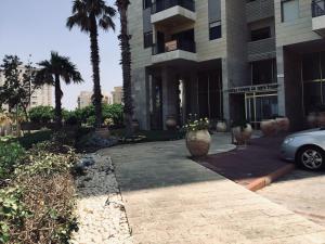 内坦亚2 BDR Nitza appartment with balkony的棕榈树建筑前的停车场