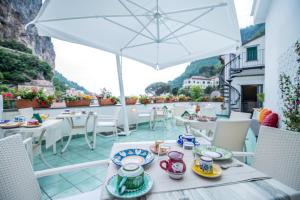 阿马尔菲Valle d'Amalfi Suites的阳台上摆放着带餐盘的桌子和雨伞