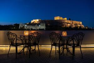 雅典卫城景色酒店的夜间阳台上的桌椅