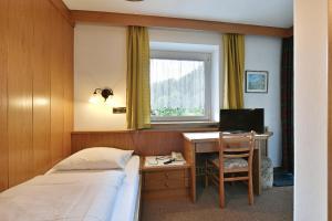 奥蒂塞伊Hotel Garni Vanadis的一间卧室配有一张床和一张带电脑的书桌