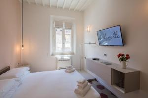芬奇Bellavalle ROOMS Vinci Florence Tuscany的白色的卧室设有床铺和墙上的电视
