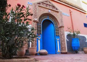 扎古拉Riad De Rêve的粉红色建筑中一扇蓝色门,上面有植物