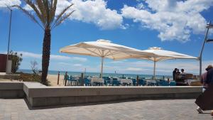 卡拉费尔BEACH & DREAMS CALAFELL的海滩上带桌子和遮阳伞的庭院