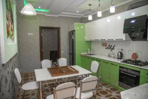 撒马尔罕Favorite apartment的厨房配有绿色橱柜和桌椅