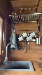 尤卡尔内Labrags Saulrieti的厨房水槽,墙上有杯子和餐具