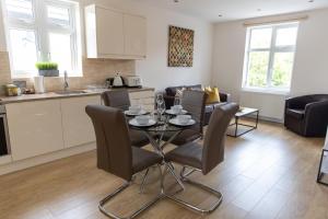 哈罗London Northwick Park Serviced Apartments by Riis Property的厨房以及带桌椅的起居室。