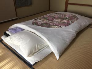 伊东Hinodeya的地板上配有带枕头的白色床