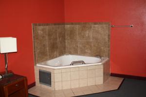 威奇托福尔斯威奇托福尔斯行政汽车旅馆的浴缸位于红色墙壁的房间