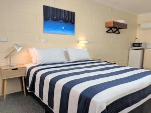 耶蓬风帆汽车旅馆的一间卧室配有一张带蓝白条纹毯子的床