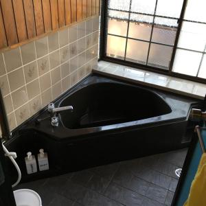 日南まるで一国一城の主 佐藤邸的带黑色浴缸的浴室,设有窗户