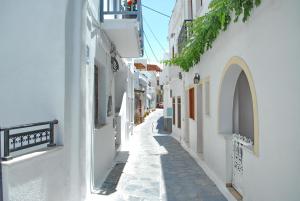 纳克索乔拉Grandma's Elegant Apartment in Naxos Town的一条有白色建筑的小巷,一个人沿着这条小巷走下去