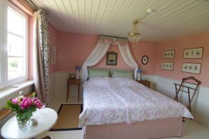 塞勒姆Bed & Breakfast mit Charme- Aux2platanes- Außergewöhnlich schön am Bodensee的粉红色的卧室,配有一张床和花瓶