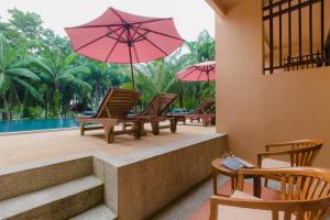 蔻立Khaolak Mohin Tara Resort - SHA Certified的一组椅子,配有遮阳伞和游泳池