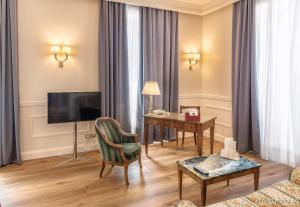 都灵西太大酒店的客厅配有书桌和电视。