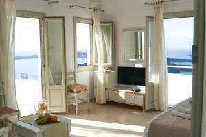 易莫洛林Irida - Santorini的一间卧室设有一张床、一台电视和窗户。