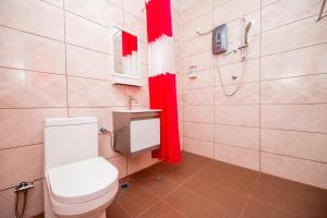 珍南海滩D’ Village Cottage的一间带卫生间和淋浴的浴室以及红色窗帘