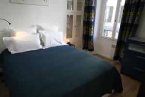 尼斯la terrasse的一间卧室配有蓝色的床、白色枕头和窗户