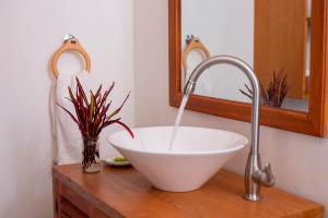 阿鲁沙Mambo Hideaway的浴室的木制柜台上有一个白色的碗水槽
