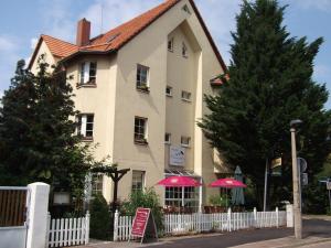萨勒河畔哈雷Pension & Café Am Krähenberg的前面有粉红色伞的房子