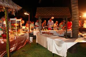 蔻立木达拉海滩别墅Spa度假酒店的一群人站在桌子旁吃着食物