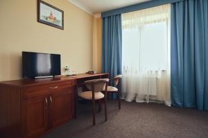 利沃夫Hotel Patriarshyi的酒店客房设有一张书桌、一台电视和一个窗户。