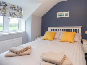 盖尔文Talfan Cottage的一间卧室配有一张带黄色枕头的大床