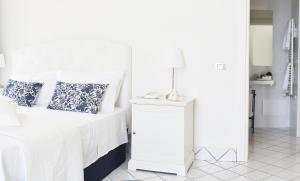 阿格罗波利帕拉左多加纳度假酒店的白色的卧室配有一张床和一张桌子上的台灯
