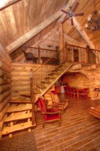 Saint-Tite-des-Caps圆木流度假屋的小木屋内的螺旋楼梯,配有红色椅子