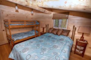Saint-Tite-des-Caps圆木流度假屋的小木屋内一间卧室配有两张双层床