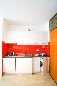 比比翁Residence Giuliana的厨房配有白色橱柜和红色瓷砖