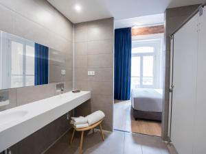 马德里room00 Gran Vía Hostel的浴室设有床、水槽和镜子